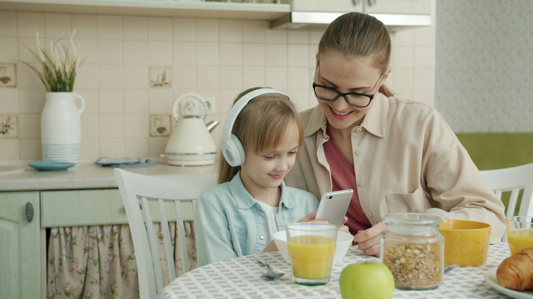 Caregiver and child sharing a phone at home