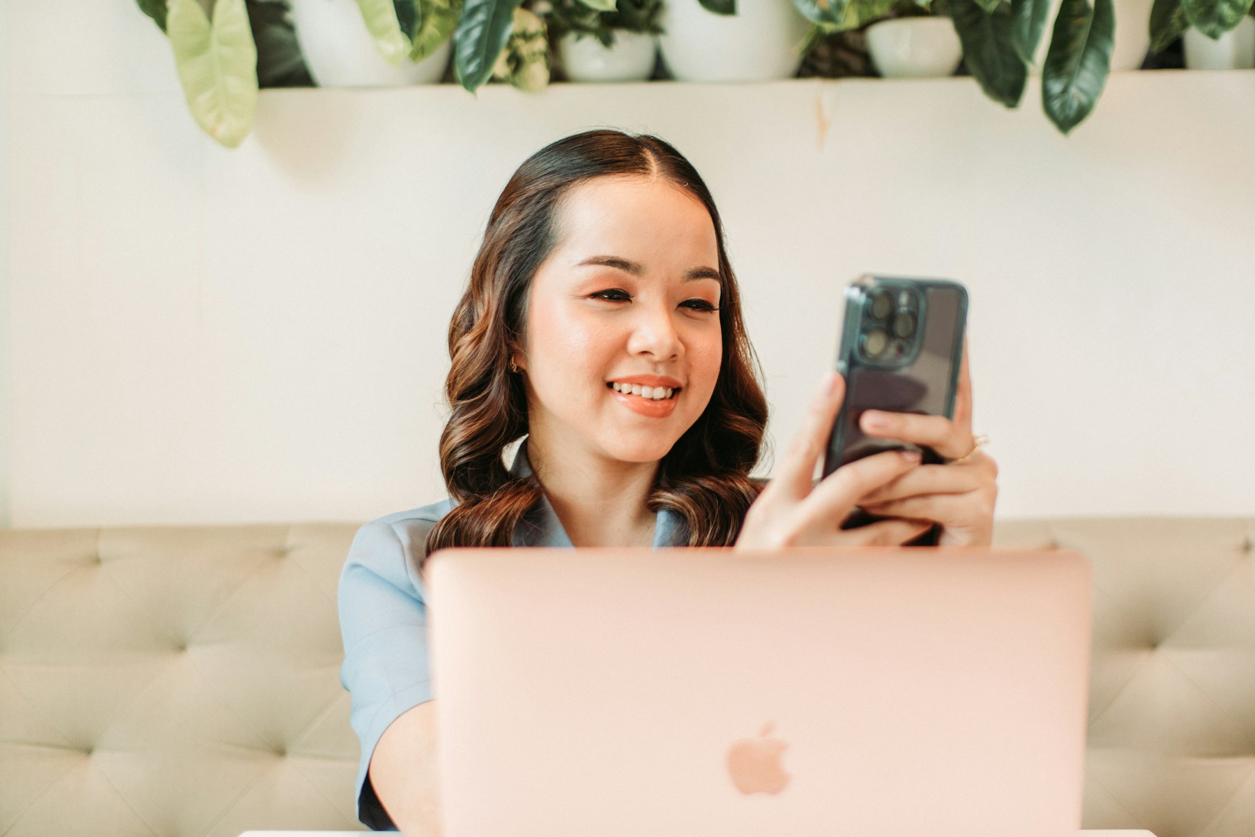 Person checking a phone beside a laptop at home
